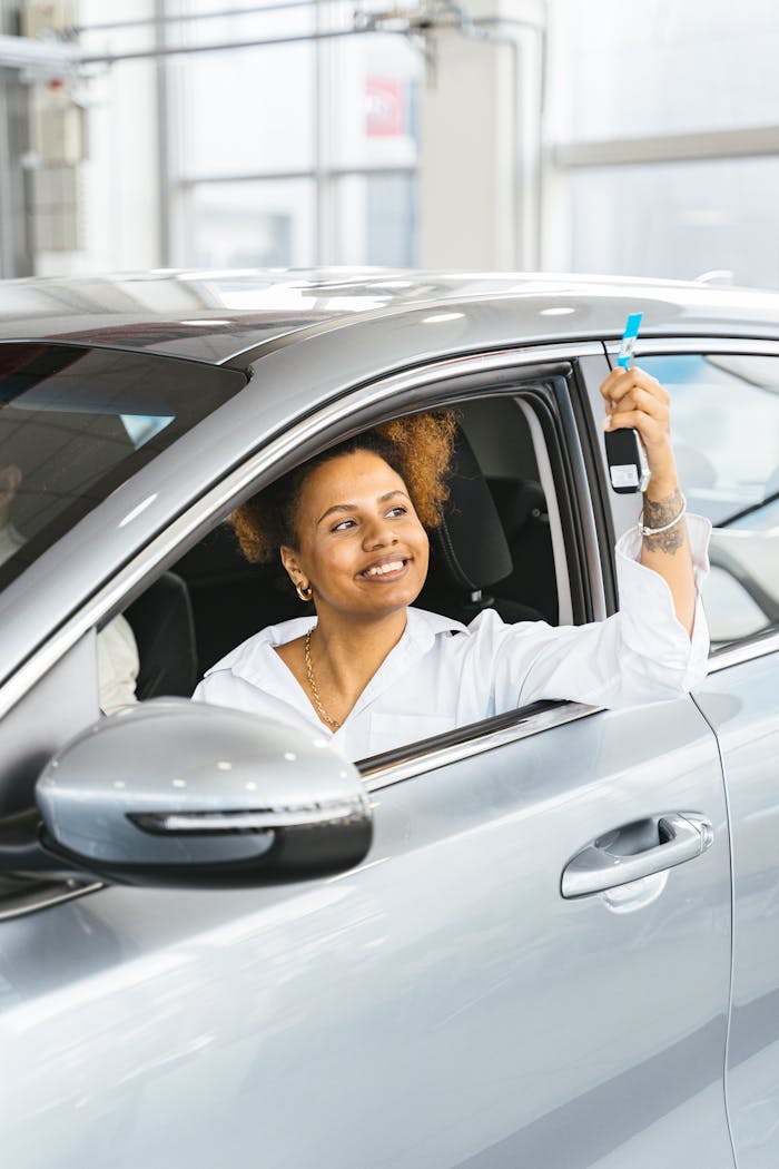 Smiling woman holding car keys from drivers seat in a new car